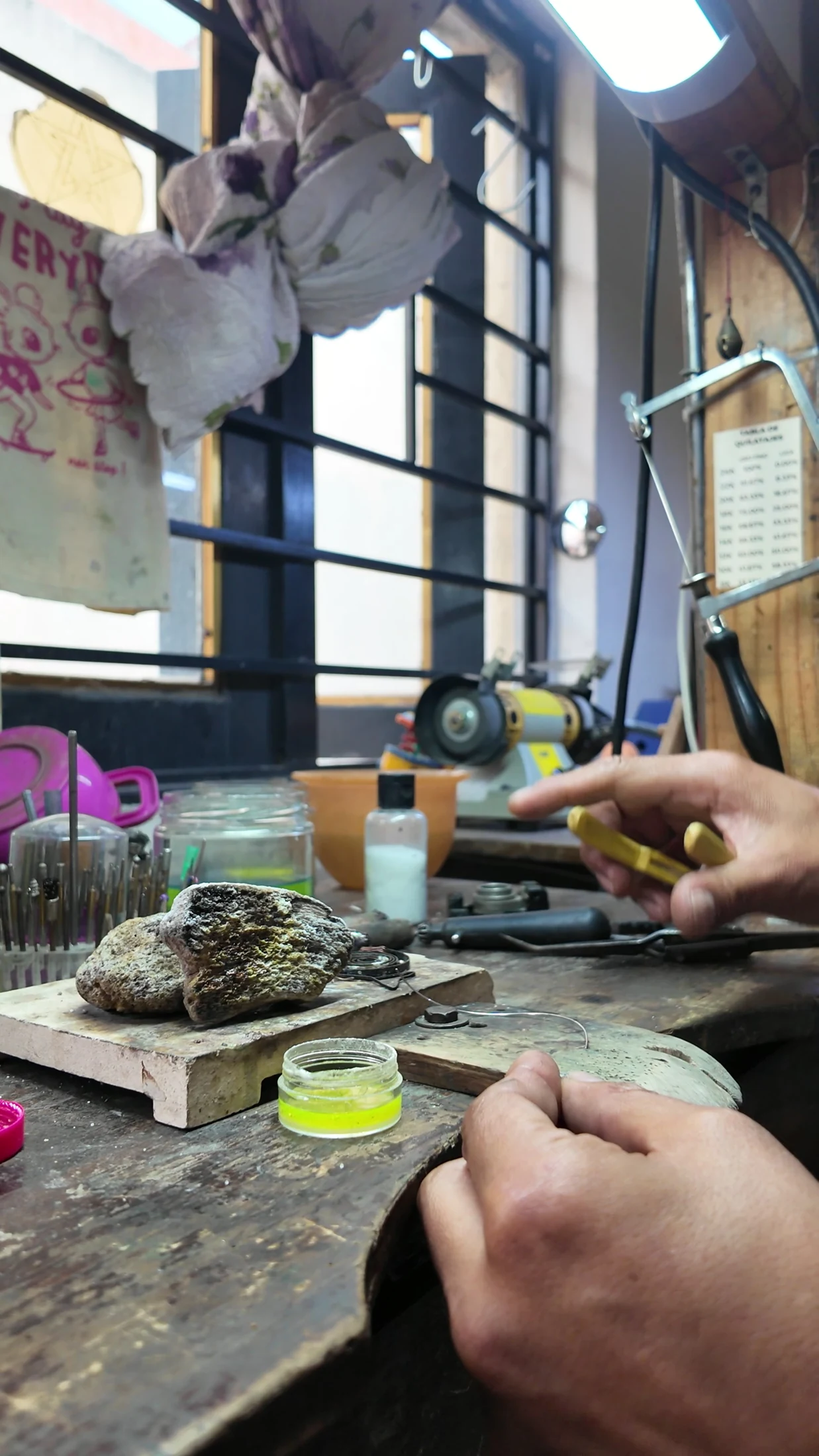 Hands and jewellery tools at a workshop bench.