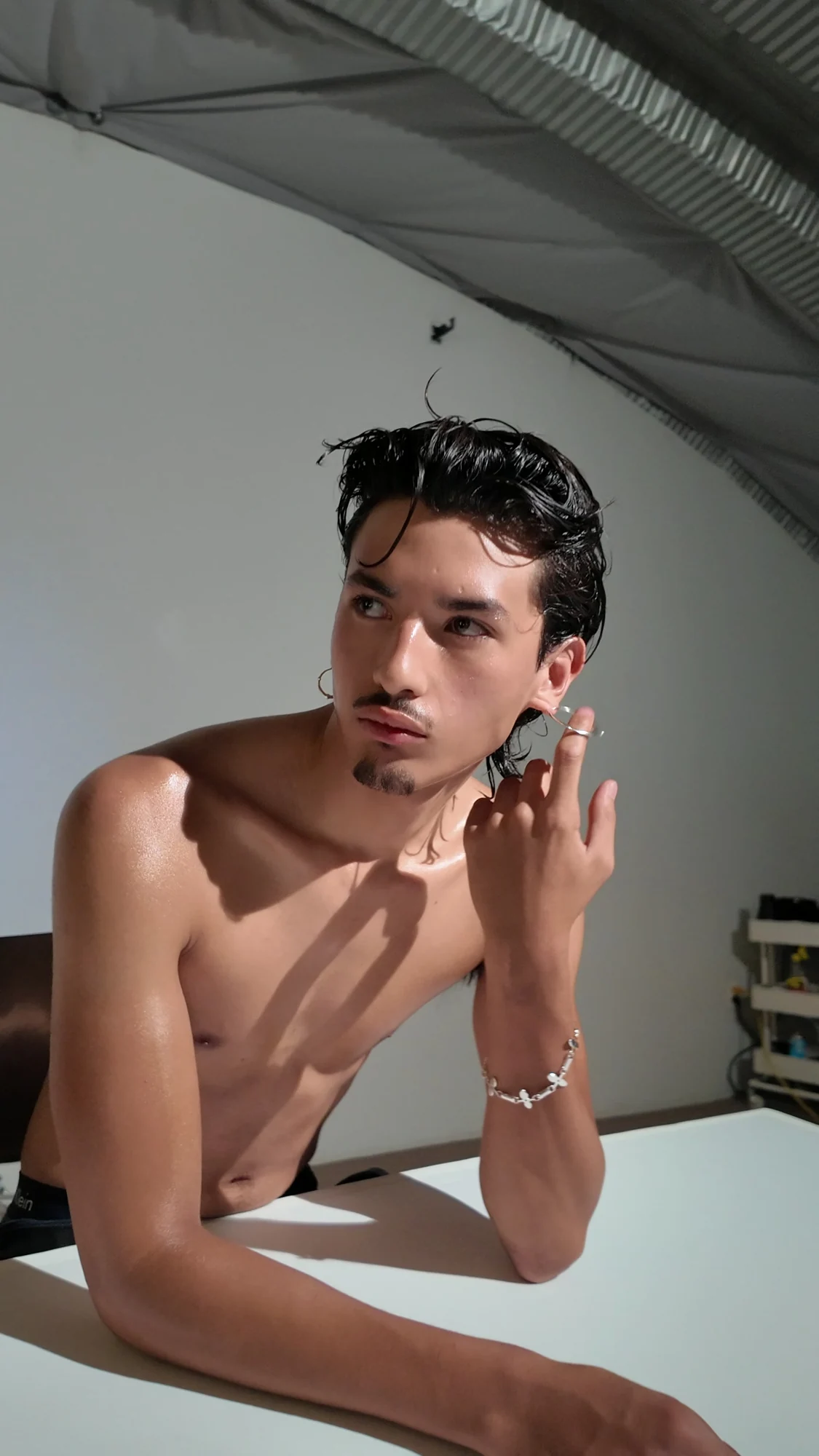 A model touching an earring beside his face.