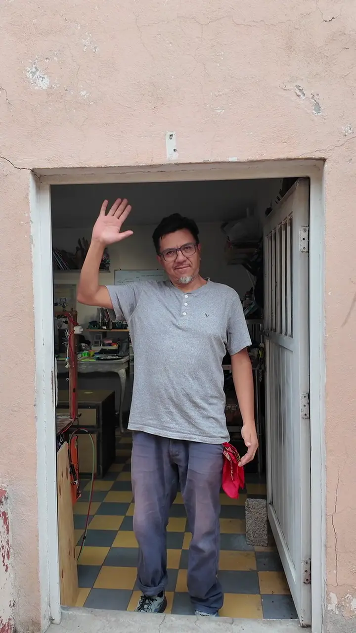 Jorge waving from the doorway of his workshop.