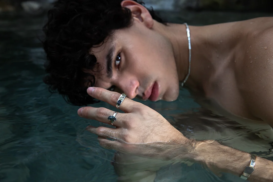 A hand wearing silver rings at the surface of the water