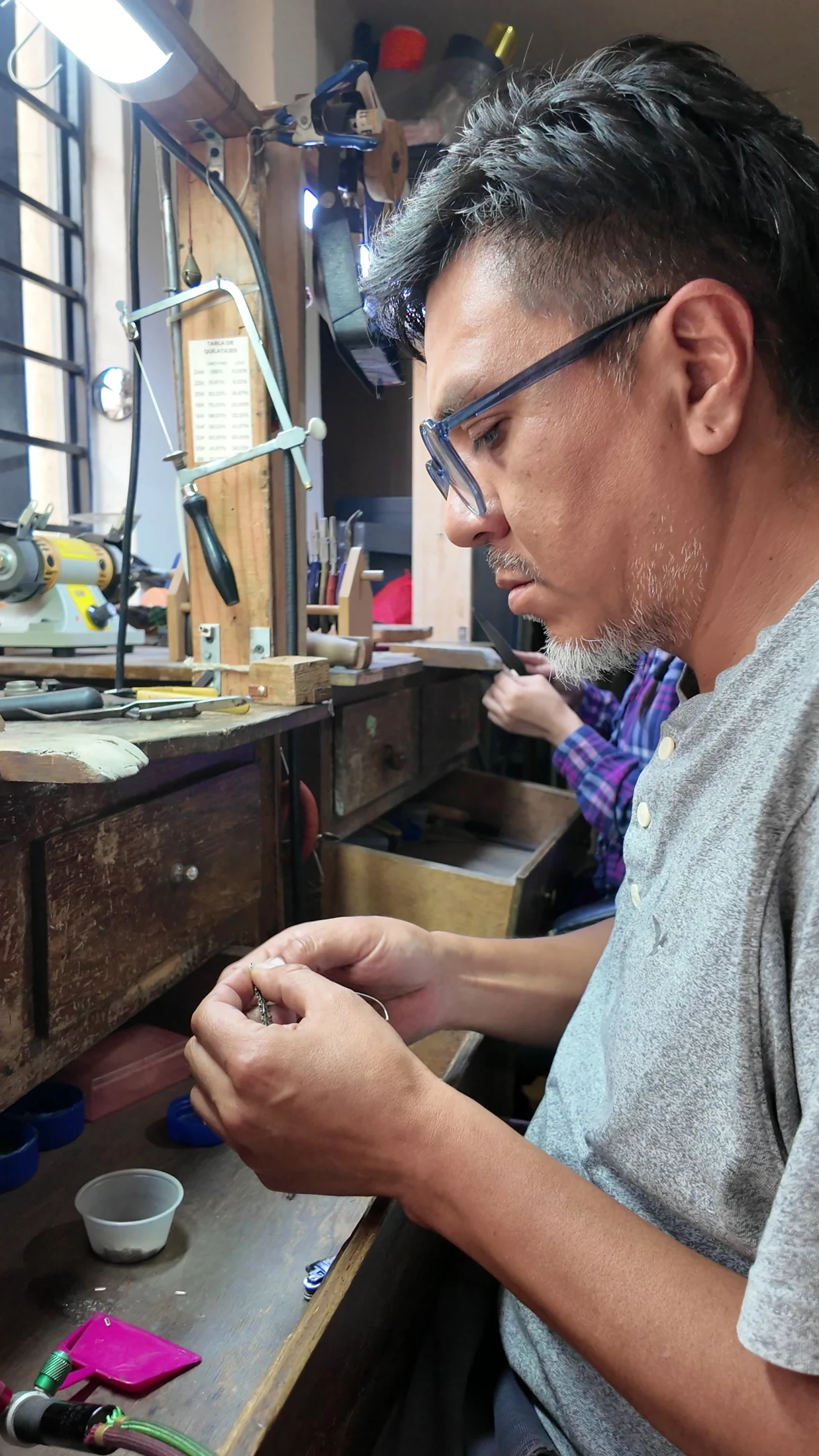 Jorge examining a small jewellery component at his workbench.