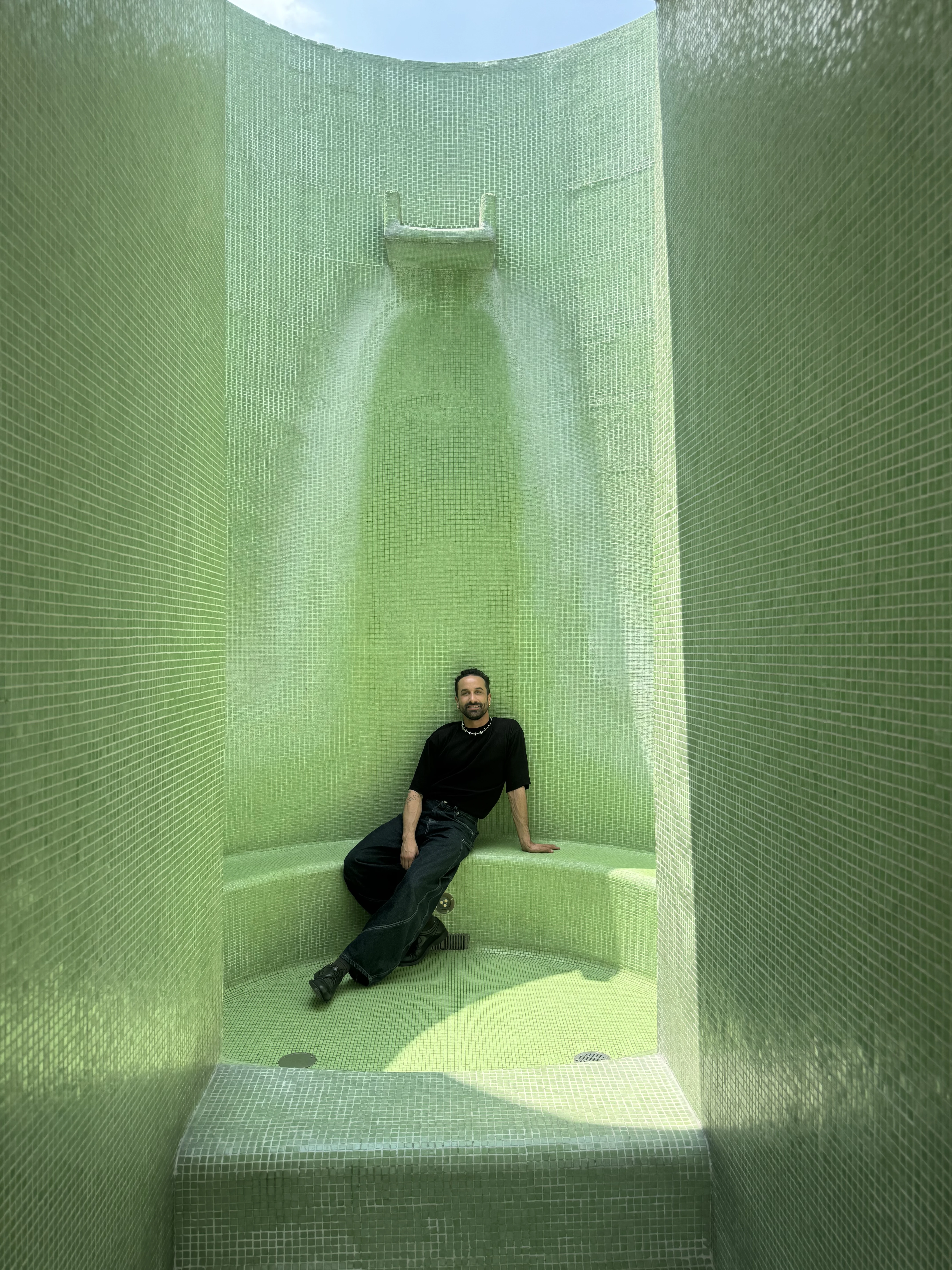 Sergio seated against green mosaic tiles.